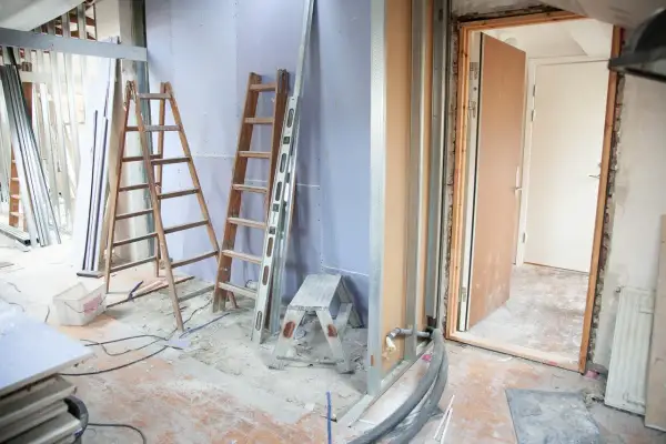 Remont mieszkania: drabiny, materiały budowlane i otwarte drzwi.